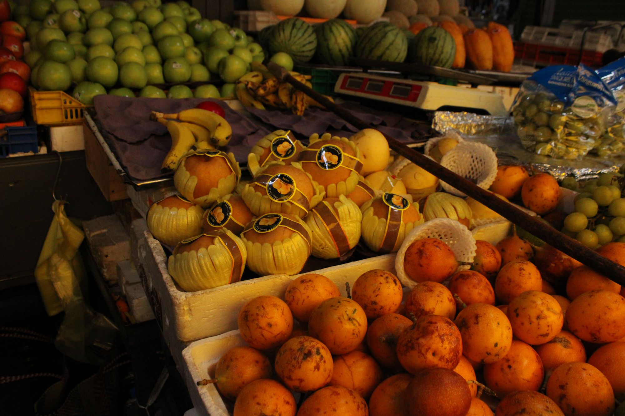 Melons and oranges stacked at a market stall